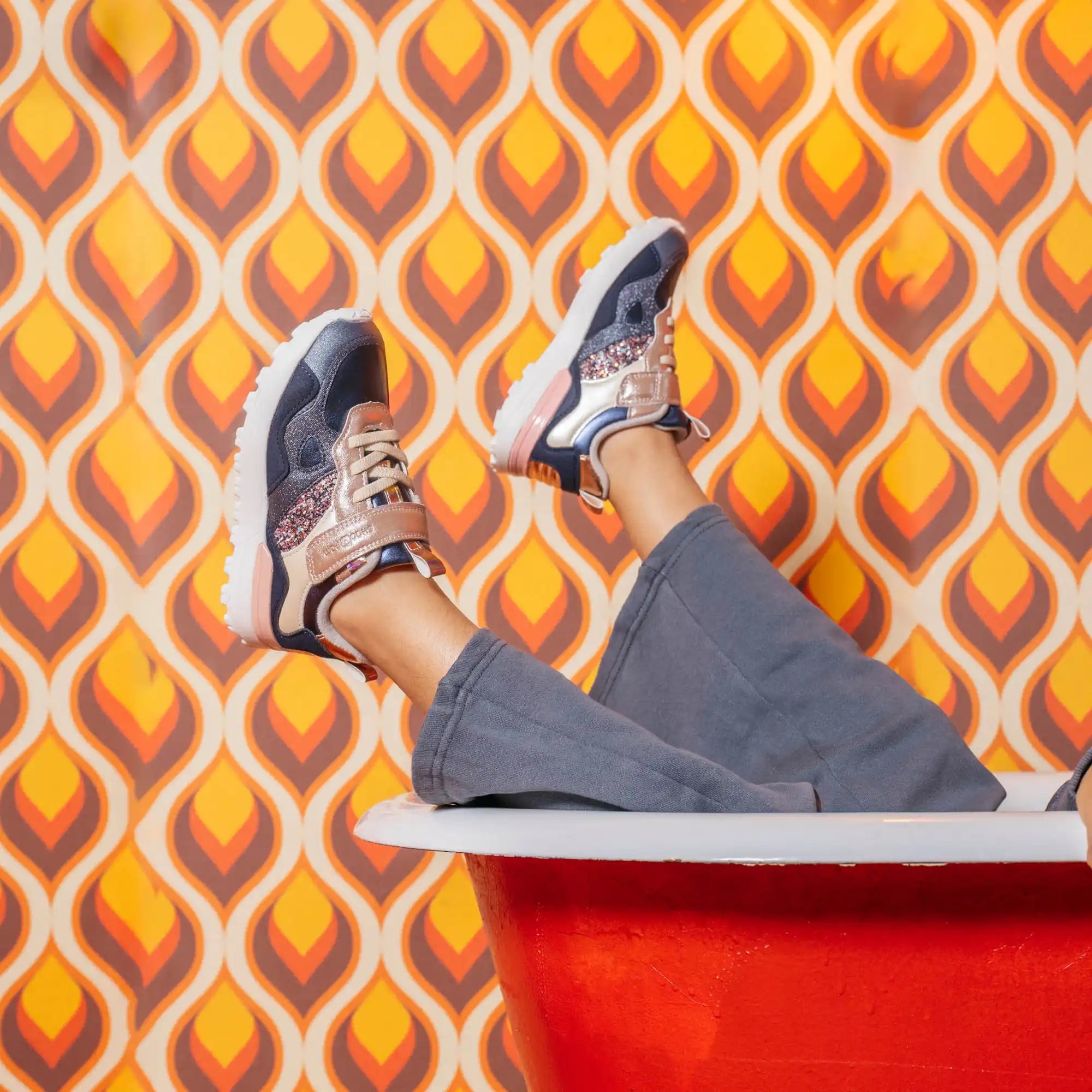 Une paire de baskets de couleur foncée avec des accents roses et dorés.