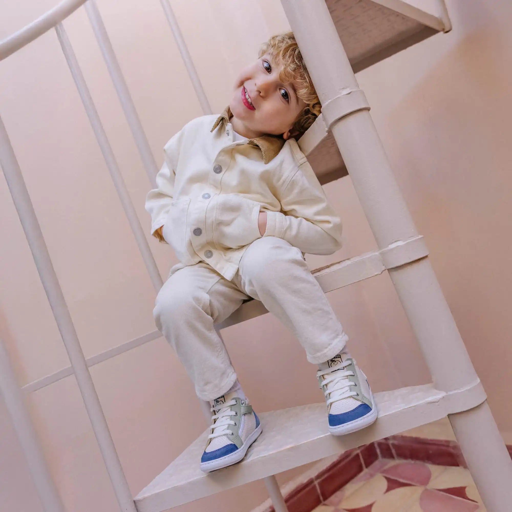 Enfant assis sur un escalier en colimaçon.